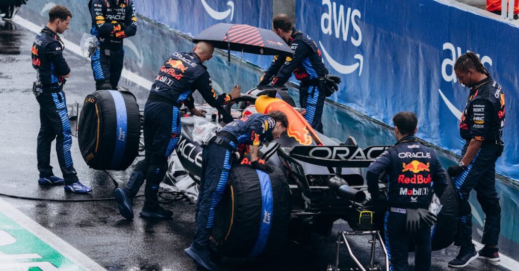 Team working on a Formula 1 car during a wet race pit stop, showcasing teamwork and precision.